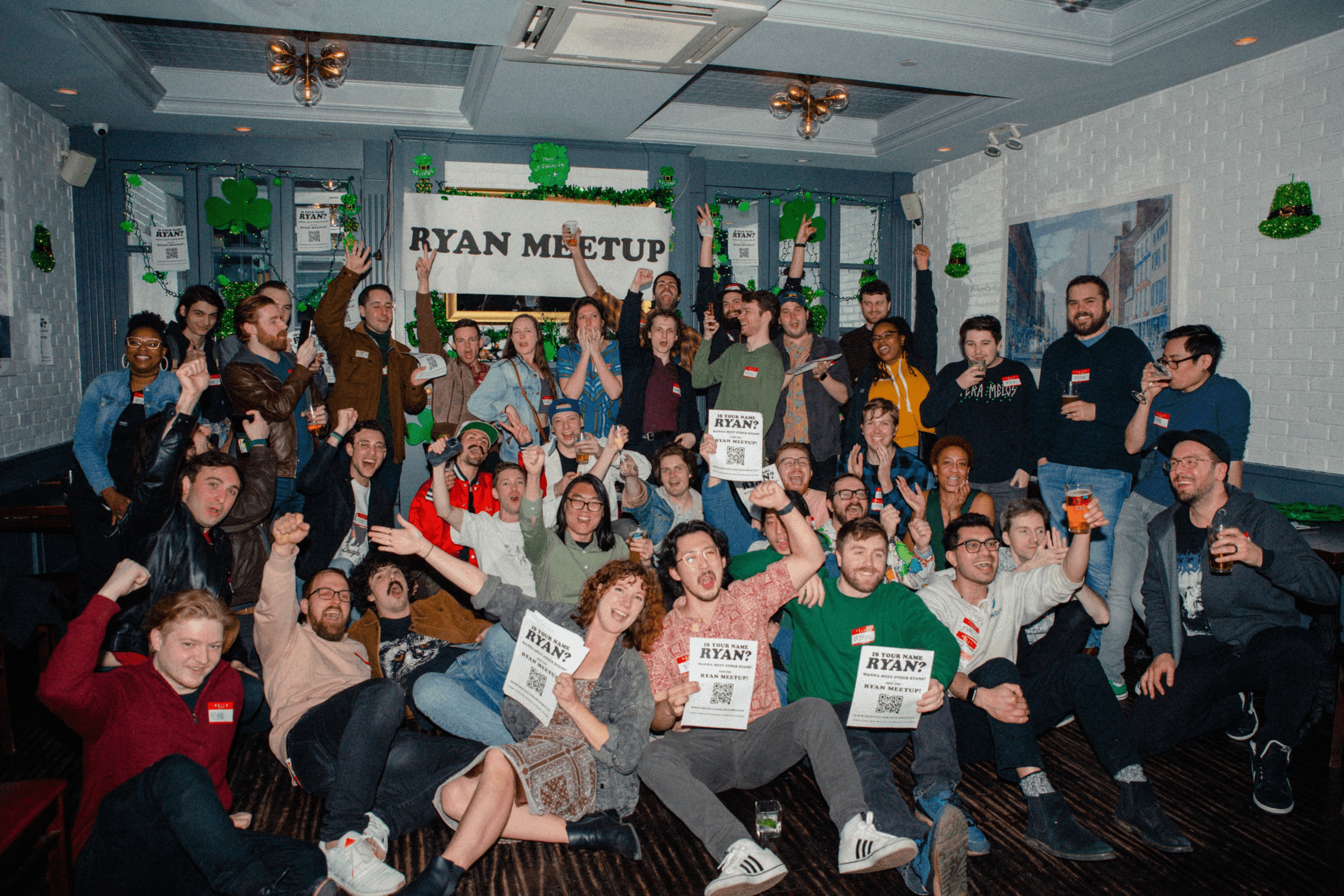 A room full of Ryans posing together under a Ryan Meetup banner